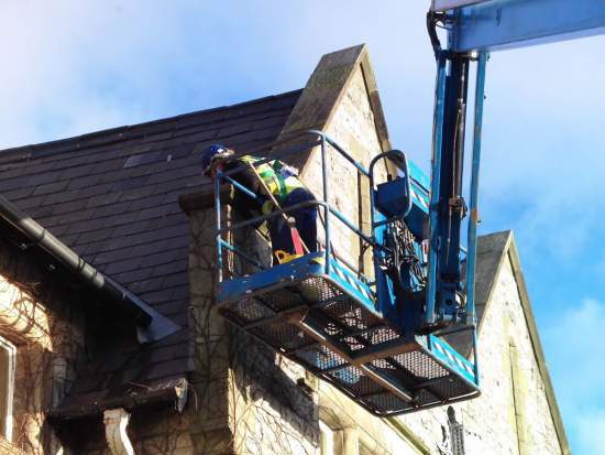 Gutter maintenance from a cherry picker at Robertson Research, Llandudno